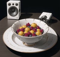 a bowl of fruit on a table next to a speaker